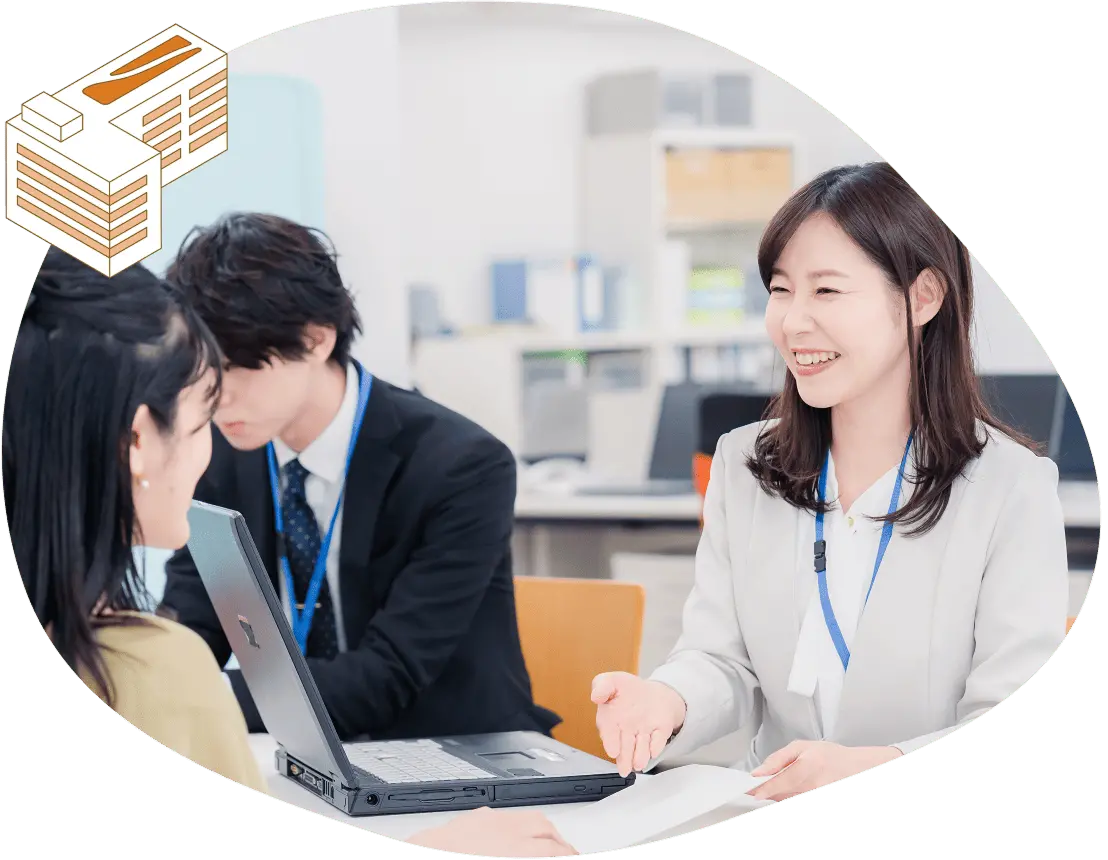 女性スタッフがノートパソコンを使いながら顧客に説明し、和やかに商談している様子を表した写真。