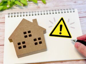 家の模型と注意マーク